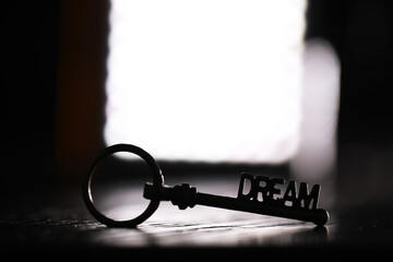 Silhouette of Key with 'Dream' Text Against Bright Light - Metaphor for Opportunity and Aspirations