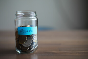 Donation Jar Filled with Coins on Wooden Table for Charity and Fundraising Campaigns