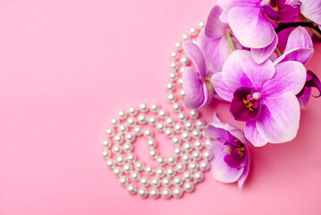 Pearl necklace and Purple orchid on pink background
