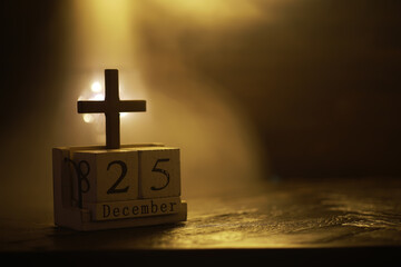 Wooden Block Calendar with Cross Displaying December 25th in Warm Ambient Light