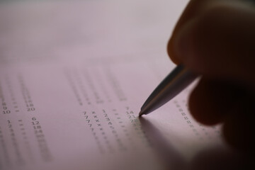 Close-Up of Hand Holding Pen Solving Math Problems on Paper
