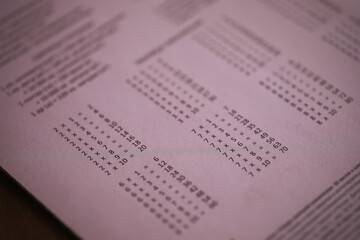 Close-up of Language Translation Chart on Pink Paper with Various Alphabets and Symbols