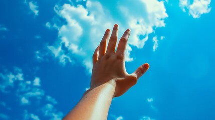 A person's hand reaching up to the sky with clouds in the background