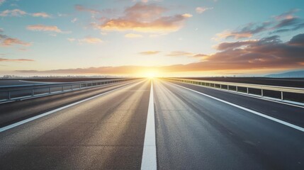 Fototapeta premium Empty highway at sunrise, showcasing an expansive road stretching towards a bright horizon under a vibrant morning sky with clouds.