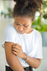 Young African woman scratching arm skin, concept of dry skin, allergic skin inflammation, body...