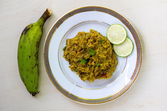 Tasty Kacha kola bhorta or Kachkola vorta in a white ceramic bowl on a wooden background. It is traditional Bengali (Bangladeshi) food. Top view.