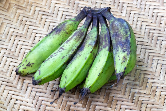 Bunch of raw bananas or green bananas on wicker basket background.