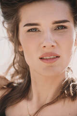 Portrait of an attractive woman in a black dress sits on the sand in the desert and the wind...