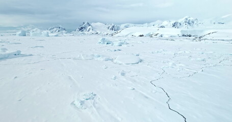 Towering mountains desert snow covered Antarctic landscape. Aerial drone fly over frozen ocean coast, ice floe crack. Beautiful South Pole winter wild nature footage. Antarctica travel and exploration