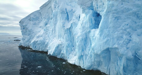 Beautiful Antarctic blue ice glacier towering polar ocean. Huge iceberg ice wall formation calving under bright sun, float cold water. Melting ice, global warming, climate change polar landscape © mozgova