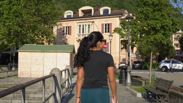 Rear View Of Hispanic Woman Roaming Around In Laveno-Mombello, Lombardy, Italy. medium tracking shot