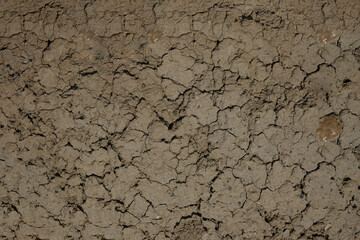Close-up top view of dry brown cracked clay land surface in a summer day. Abstract weather...
