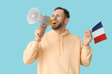 Young man with flag of France and megaphone on blue background