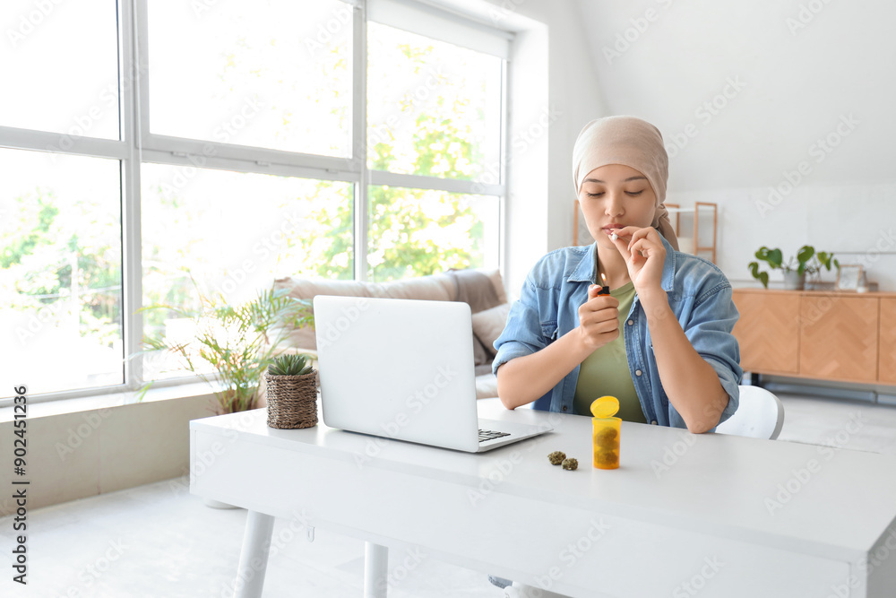 Sticker Young Asian woman after chemotherapy lighting up joint with weed at home