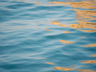 Beautiful close up sea water surface, blue water with golden sunrise reflections. Close-up of...