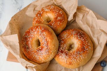 Baking paper with tasty bagels on white table