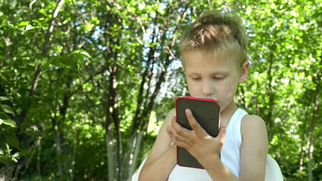 child enthusiastically playing games on a smartphone outdoors demonstrates the growing concern about the overuse of electronic devices in childhood.