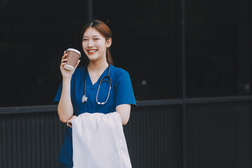 Confident nurse on her way to work in a clinic. Pretty female nurse drinking coffee and rest after...