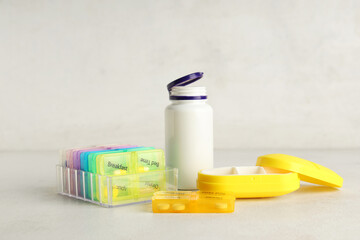 Plastic pill organizers and bottle on table against white background