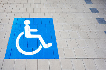 Parking for disabled people. Blue rectangular sign on the asphalt. Wheelchair logo.