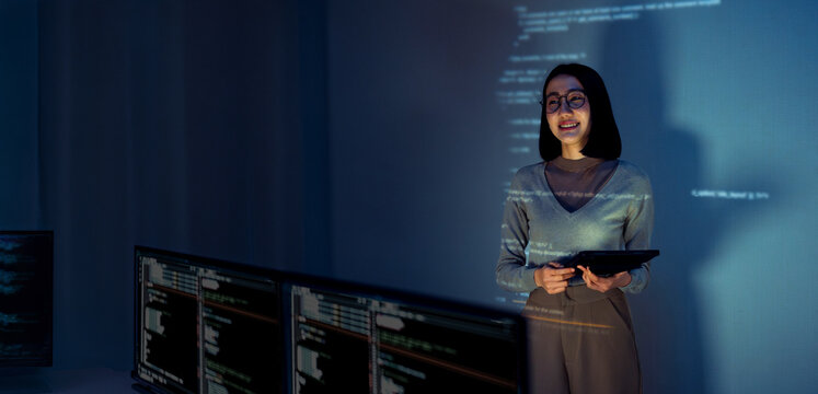 asian woman programmer standing in front of a screen with code projected  presentation the integration of technology and human expertise in software development