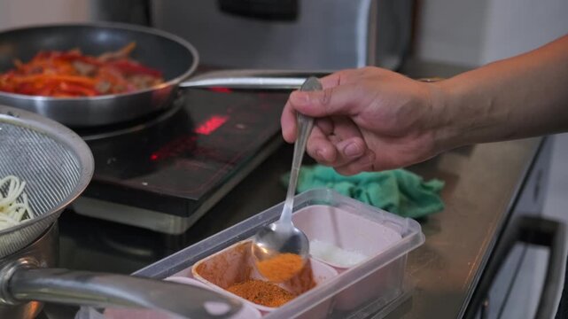 Preparation udon with beef Malasyan seasoning in spoon in chef hand on commercial kitchen, close up.