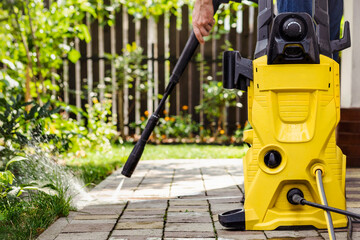 Pressure Washing Paving Slabs Floor in Patio Garden. High Pressure Cleaner Karcher for Cleaning...
