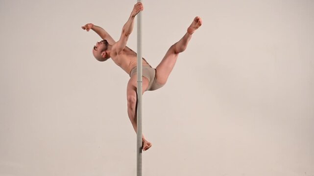 Male pole dancer performing poses on white background