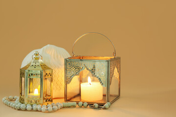 Muslim lamps with burning candles, prayer beads and hat on color background