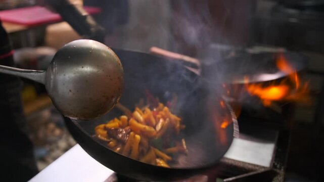 Cooking in boiling oil frying meat and french fries, Chef hands prepares meal in flambe style in cafe kitchen on gas stove.