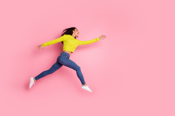 Full length photo of sporty youth funny girl wearing green sweater and jeans jumping catching object in air isolated on pink color background