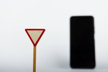 Wooden Yield Sign with Blurred Smartphone