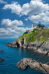 Disparo vertical al hermoso faro marítimo sobre peñón de roca en la villa de Cudillero, España....