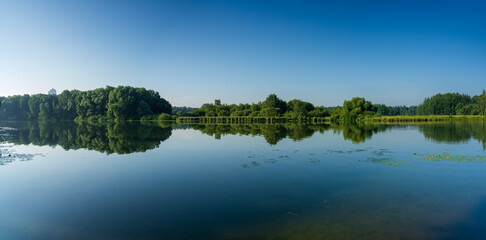 Reflection of trees in the lake. Panoramic view of the banks of the river bay