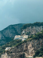 Obraz premium A mountain with a small house on top of it. The house is surrounded by trees and the sky is cloudy