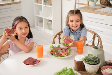 Cute little girls with tasty toasts at table in kitchen