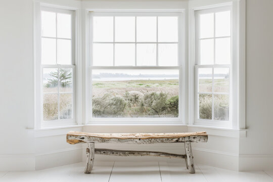 Rustic wooden bench in front of a bay window with a view of a lake and grassy field