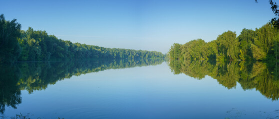 Reflection of trees in the lake. Panoramic view of the banks of the river bay