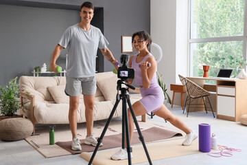 Couple of sports bloggers with dumbbells recording video at home