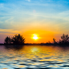 Obraz premium dramatic sunset over a calm lake with forest silhouette on coast