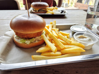 Close-up cheeseburger and French fries on metal tray. Real food.