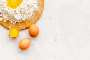 Making dough concept. Pile of flour and eggs on white background top view copy space