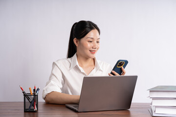 Young female businessman sitting at desk on white background