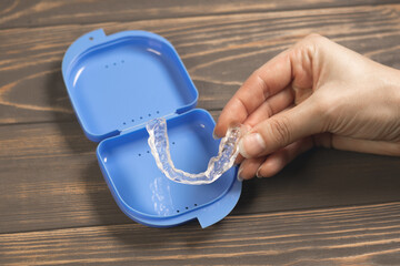 Woman takes Dental splint mouth guard from the box. TMJ splint disorder treatment. Occlusal splint. Prevent bruxism. Mouth guard for TMJ. Teeth protection. Pain in jaw. Teeth grinding.