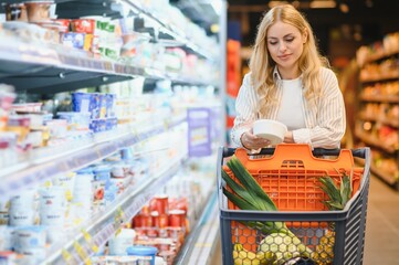 Young woman looking at product at grocery store. Costumer buying food at the market