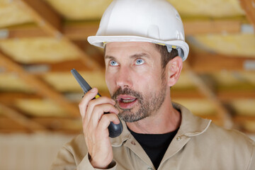 male builder in hardhat with walkie talkie