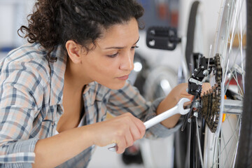 female mechanic using spanner to tighten nut on bicycle wheel