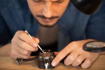 middle aged repairman working on an old clock in workshop