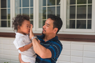 A caring dad wiping the tears from his young toddler's son while comforting him, after a tantrum...