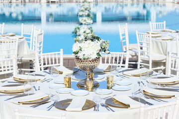 Romantic poolside wedding setup with white chairs and white linens